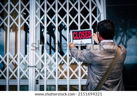 Businesswoman closing her business activity due economy crisis putting closed sign on the door of his store. Concept of bankrupt and shotdown commercial job occupation. Back view of man Royalty-Free Stock Photo #2151694321