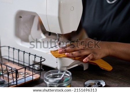 Hand of young black woman sewing part of new fashionable piece of clothing Royalty-Free Stock Photo #2151696313