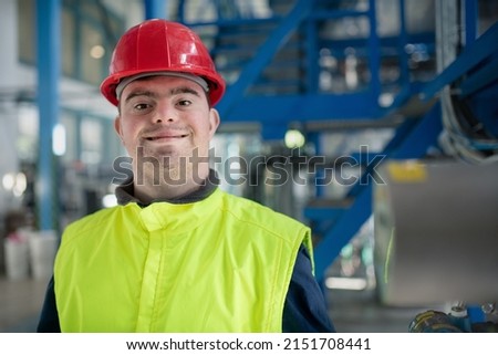Young man with Down syndrome working in industrial factory, social integration concept. Royalty-Free Stock Photo #2151708441