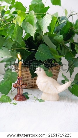 Dove figurine, church candle and birch leaves on wooden table. Dove - symbol of Holy Spirit. Holy Trinity Sunday. festive traditional composition for Pentecost day. concept of faith, God.