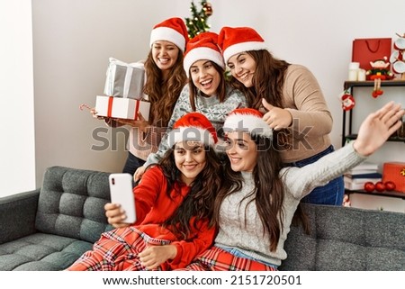 Group of young hispanic women on christmas meeting make selfie by the smartphone at home.