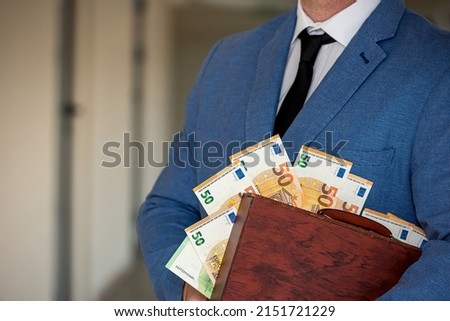 young boss businessman in expensive suit with tie holds suitcase with euro banknotes. The concept of the euro in a suitcase for a man with the tax