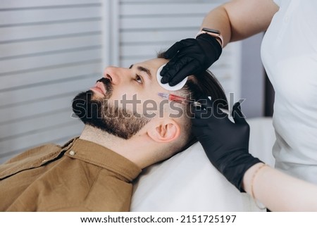Stylish bearded man visiting aesthetic clinic, getting lips filler, closeup. Attractive Man having beauty injection at male spa salon background. Anti-aging treatment for men concept  Royalty-Free Stock Photo #2151725197