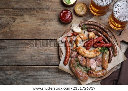 Set of different tasty snacks and beer on wooden table, flat lay. Space for text
