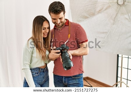 Professional photographer showing camera photos to model at photography studio.