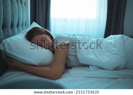 Side view of young beautiful woman dreaming in bed and relaxing at night. High angle view of woman with closed eyes sleeping well at home in the dark. Beautiful girl sleeping peacefully  Royalty-Free Stock Photo #2151733635