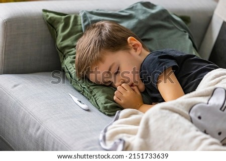 Unhealthy little boy child measure high temperature with thermometer sleep in bed relax at home in bedroom. Sick ill little kid suffer from flu fever asleep in bed on lockdown quarantine. Royalty-Free Stock Photo #2151733639
