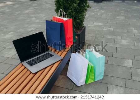 Top view Laptop with black screen and shopping bags in the mall. Online shopping concept