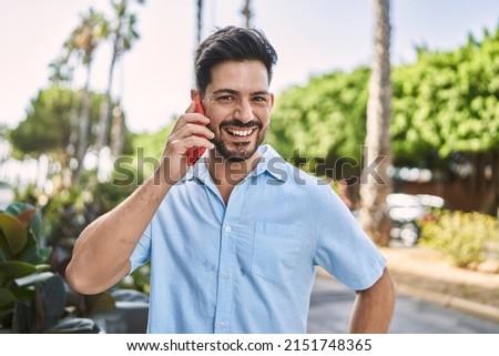 Young hispanic man smiling happy talking on the smartphone at the city.