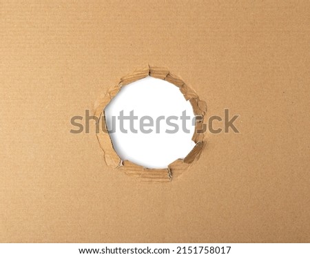 Cardboard hole background. Carton torn with copy space, kraft paper frame top view