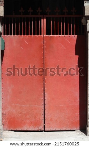 A picture of a red iron door with fine bars on it. It's a door of an old traditional apartment in Hsinchu City, Taiwan. Can be used as background related to travel.