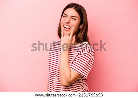 Young caucasian woman isolated on pink background showing rock gesture with fingers