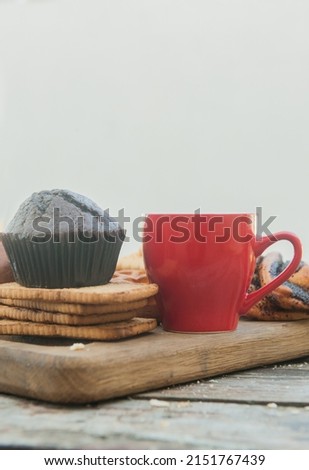 Empty space template with chocolate muffin and red cup of coffee in outdoor city cafe