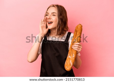 Young baker caucasian woman isolated on pink backgroundshouting and holding palm near opened mouth.
