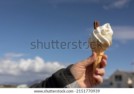 woman's hand holding a freshly made ice cream cone  up against a spring blue sky 