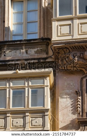 Abstract picture of arabic style balconies on a limestone building in Valetta, Malta, creating a charming textured background with lots of old wood and detailed stone carvings. 