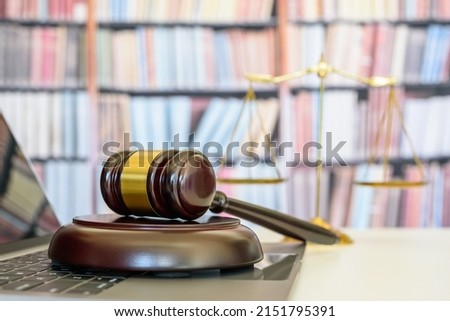 Legal office of lawyers, justice and law concept : Judge gavel or a hammer and a base used by a judge person on a desk in a courtroom with blurred weight scale of justice, bookshelf background behind. Royalty-Free Stock Photo #2151795391