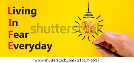 LIFE living in fear everyday symbol. Concept words LIFE living in fear everyday on yellow background. Businessman hand. Light bulb icon. Business LIFE living in fear everyday concept. Copy space.