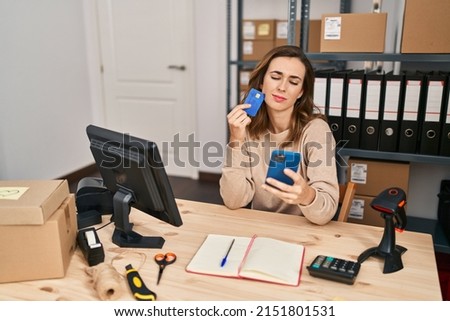 Young woman ecommerce business worker using smartphone and credit card at office
