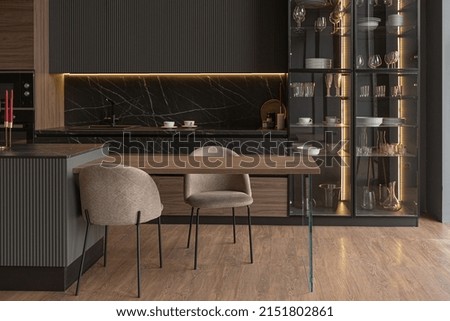 kitchen area in a chic expensive interior of a luxury home with a dark black and brown modern design with wood trim and led light Royalty-Free Stock Photo #2151802861
