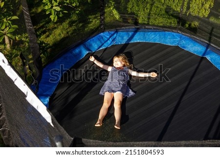 Little preschool girl jumping on trampoline. Happy funny toddler child having fun with outdor activity in summer. Sports and exercises for children. Royalty-Free Stock Photo #2151804593