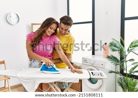 Man and woman couple ironing and hugging each other at laundry room