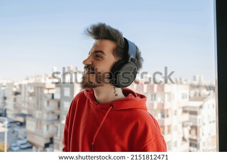 Headphone, man in red sweatshirt with headphones and listening to music on the balcony, listening to music and enjoying the moment