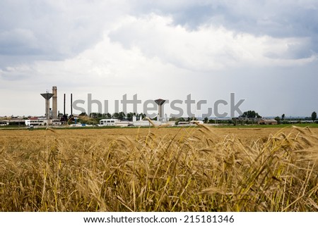 Industrial landscape with wheat field and dramatic clouds