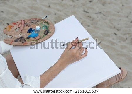 woman drawing with painting tools, oil color and wooden paint palette.