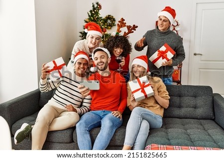 Group of young people drinking wine and holding gifts make selfie by the smartphone at home.