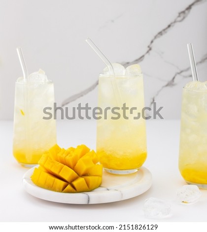 Refreshing drink with mango pulp in glasses with a glass straw on the background of a marble wall, cut mango next to the glass Royalty-Free Stock Photo #2151826129