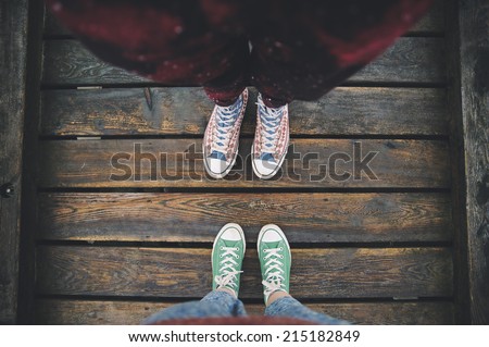 two sneakers behind each others on the wooden background as a sign of love