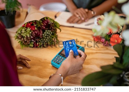 Close up of hands of woman paying bill with blue credit card by contactless to florist. Hands of woman customer make payment with credit card with NFC technology on terminal device. Royalty-Free Stock Photo #2151833747