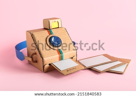 Cardboard photo camera with pictures on pink background