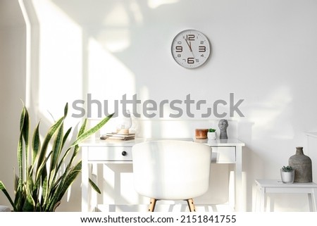 Modern workplace and clock hanging on light wall
