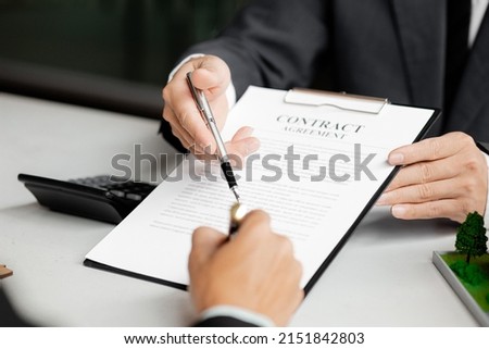 Rental company employee is discussing the details before the customer agrees to sign a rental contract, explaining the details and the terms and conditions of the rental. Real estate rental ideas.