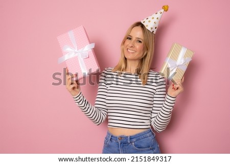 Portrait of a smiling pretty young woman holding gift boxes isolated over pink background