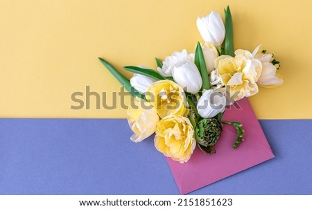 Flowers in an envelope on a colored background, flat lay.
