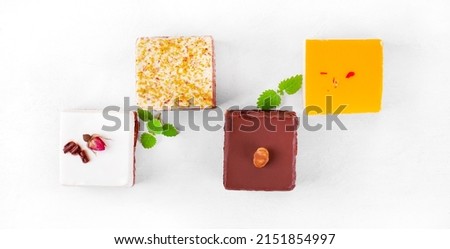 Four assorted cakes on the white table. Mousse cake with passion fruit, with chocolate, pistachio, and cheesecake. Set of serving size desserts. Top view Royalty-Free Stock Photo #2151854997
