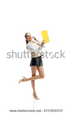 Portrait of young woman, employee in official stylish cloth talking on phone, having business call isolated over white studio background. Concept of beauty, business, ballet, art, dance style