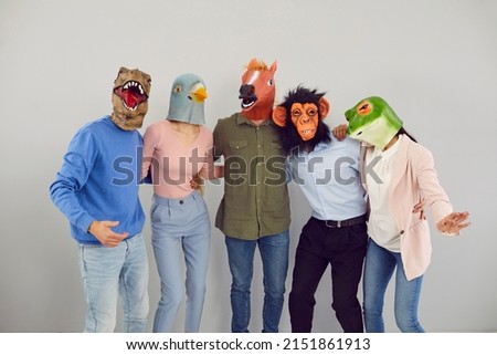Portrait of cool eccentric diverse people in animal masks isolated on grey background hug show unity. Smiling funny friends in crazy headwear have fun together enjoy relax or leisure time.