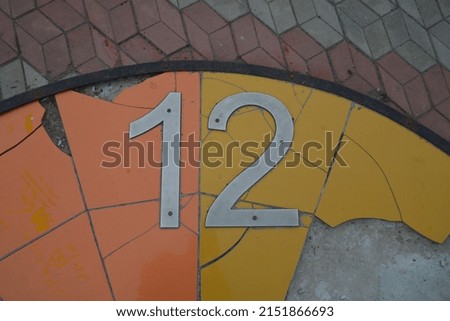 the number 12 on the background of a broken yellow-orange background and asphalt