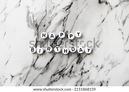 The inscription of beads Happy Birthday on a light marble background