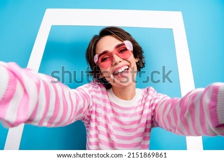 Portrait of excited cheerful woman blogger influencer make selfie with white frame isolated on blue color background