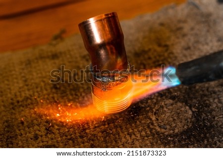 Copper soldering, installation process and soldering of copper pipes to the heating fireplace, copper elbow. Royalty-Free Stock Photo #2151873323