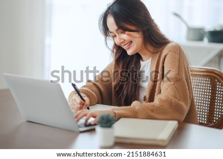 Close up happy young asian woman using laptop, writing, watching webinar, training, involved in internet lesson, motivated positive student studying online at home. education concept. Royalty-Free Stock Photo #2151884631