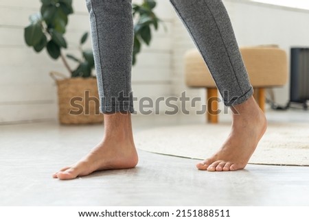 Cropped Shot Of Male Bare Feet Standing On Floor Wearing Casual Domestic Pants In Modern Bedroom. Domestic Comfort And Radiant Floor Heating System Concept Royalty-Free Stock Photo #2151888511