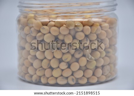 extremely close up picture of dried soy beans in plastic jar with lid