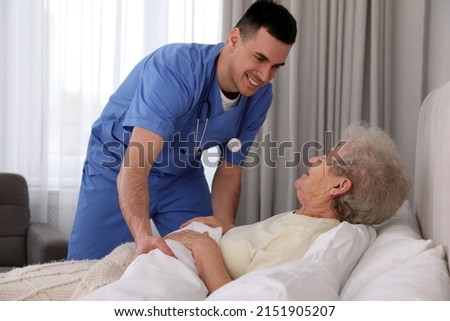 Young caregiver and senior woman in bedroom. Home health care service