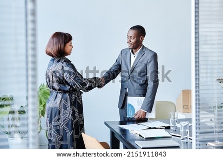 Portrait of African American business advisor shaking hands with female client after meeting in office Royalty-Free Stock Photo #2151911843